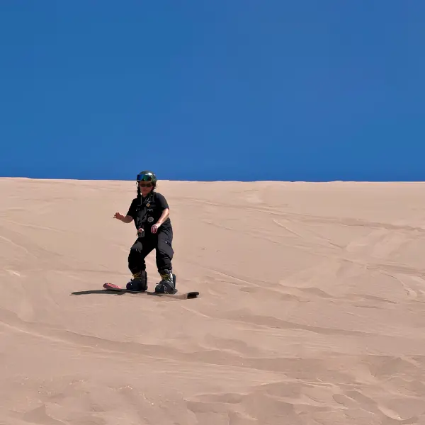 Boo Ana sandboarding down sand dune Atacama Desert Chile